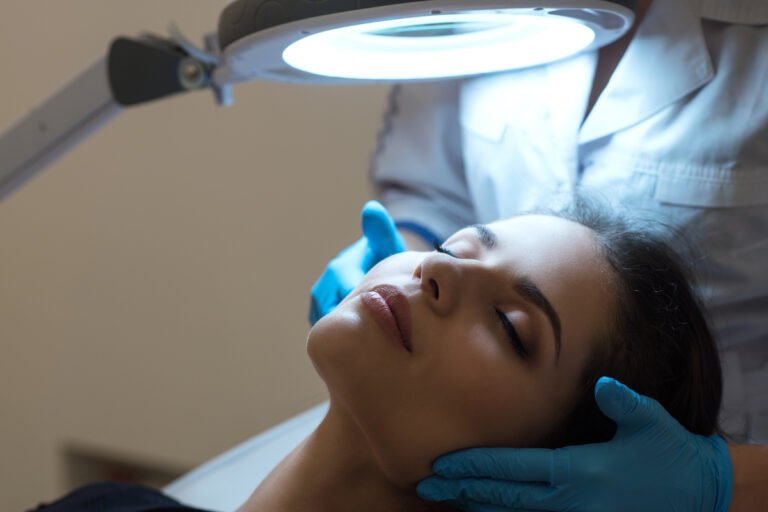 Dermatologist examining a woman’s facial skin during a professional skin treatment consultation